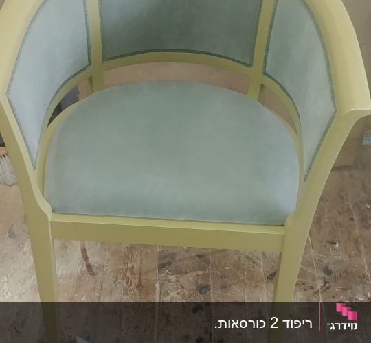 כיסא מרופד עם מסגרת ירוקה על רצפת עץ